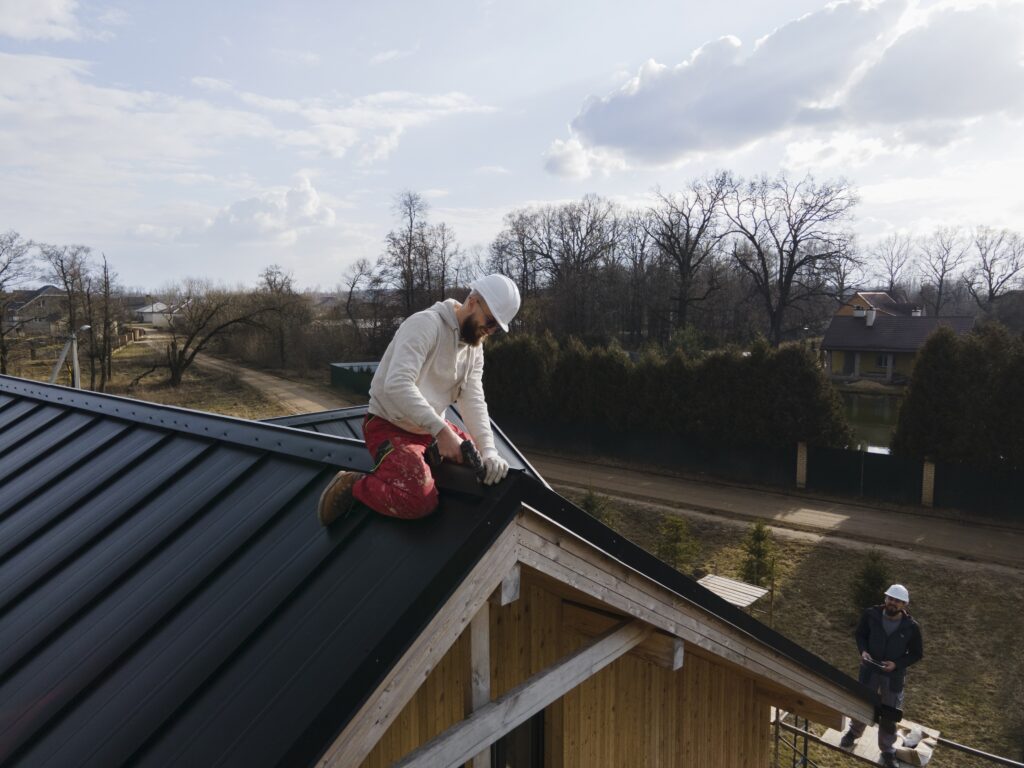 Two professional roofers work on installing a new black metal roof, an example of the quality craftsmanship provided by Billings Emergency Roofing Services by Wegner Roofing & Solar.