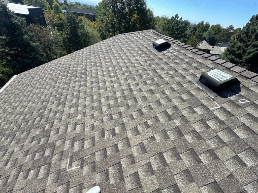 An expansive architectural shingle roof undergoing inspection, marked with chalk to highlight its durability. This is an example of the quality Bozeman Hail Proof Roofing provided by Wegner Roofing & Solar.