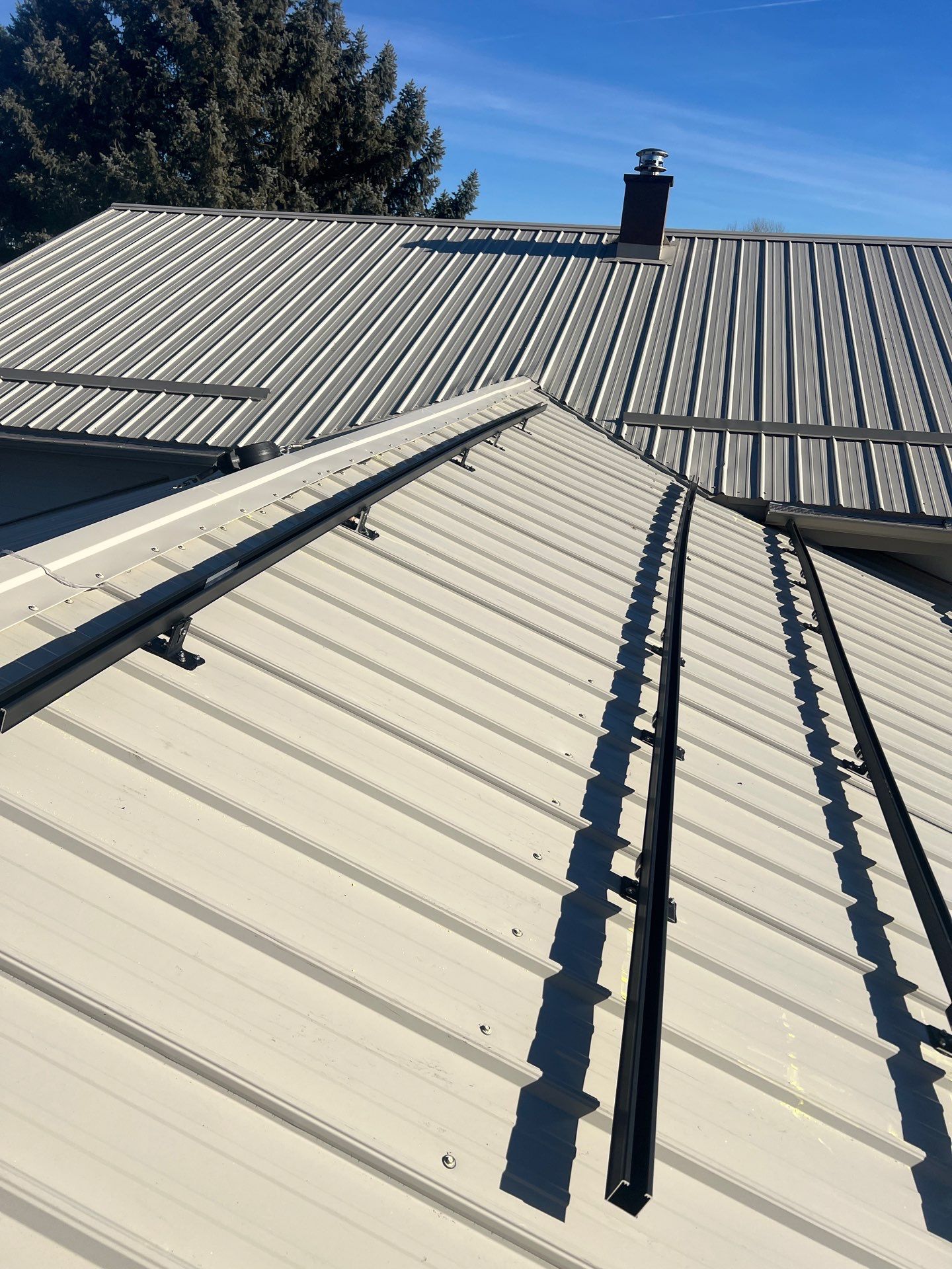 Light gray standing seam metal roofing with black snow guards installed, showcasing Bozeman Metal Roofing by Wegner Roofing & Solar.