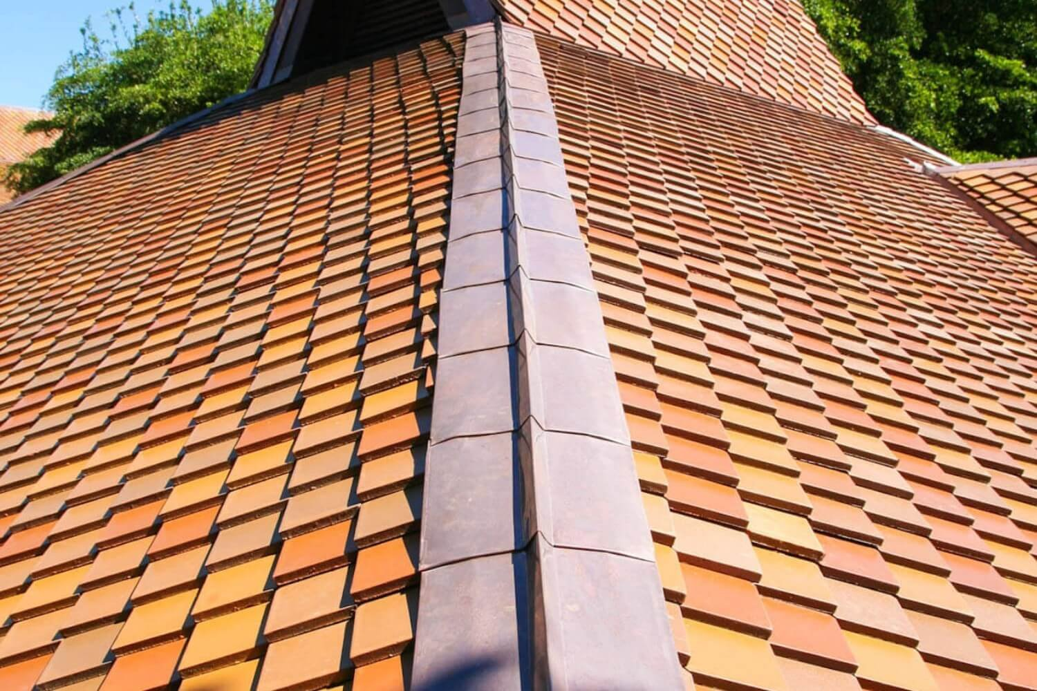 Close-up of a high-quality, textured terracotta tile roof with a contrasting metal ridge cap, demonstrating premium finished work from Charlotte NC Residential Roofing Services by Burish Builder CLT.
