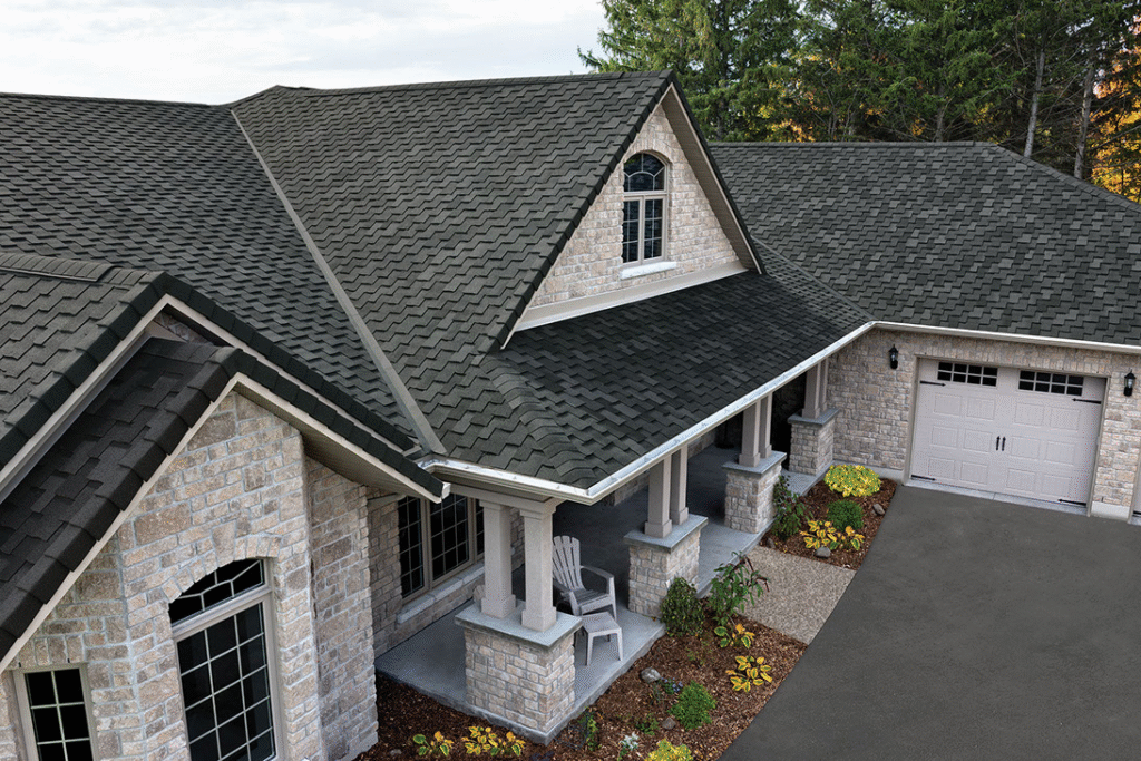 A large, beautiful home with light-colored stone siding and a complex, dark architectural shingle roof, showcasing the high-quality Columbia SC Residential Roofing Services offered by Burish Builder Columbia.