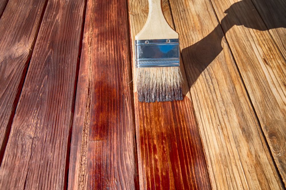 Brush applying stain on wood surface for Greensboro hardwood color correction.