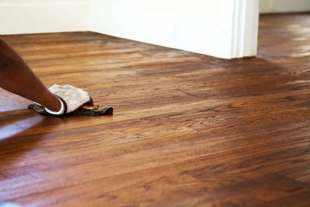 Worker applying stain by hand during Greensboro Hardwood Floor Refinishing.