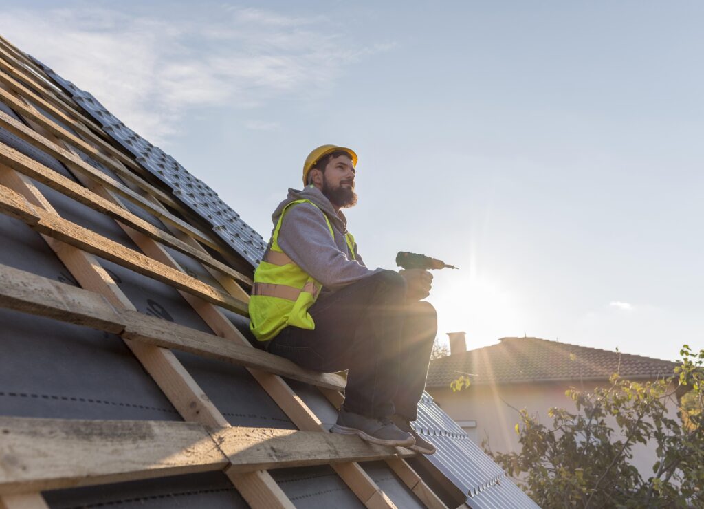 A professional roofer in a hard hat and safety vest pausing during a roofing installation, representing a high-quality Ramsey MN Roof Replacement by Pro24 Contracting, Inc.