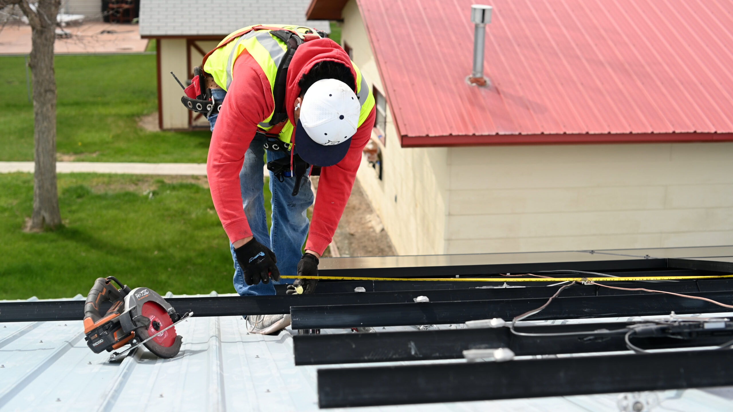 An expert from Burish Builders Wilmington, a leading Wilmington NC Roofing Company, wearing safety gear while precisely measuring a new metal roof for installation.
