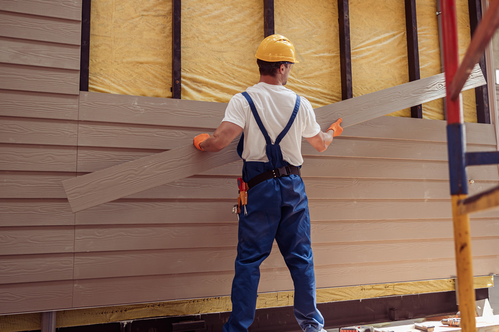 Bozeman Siding Contractors by Wegner Roofing & Solar installing new beige vinyl siding over exterior wall insulation.