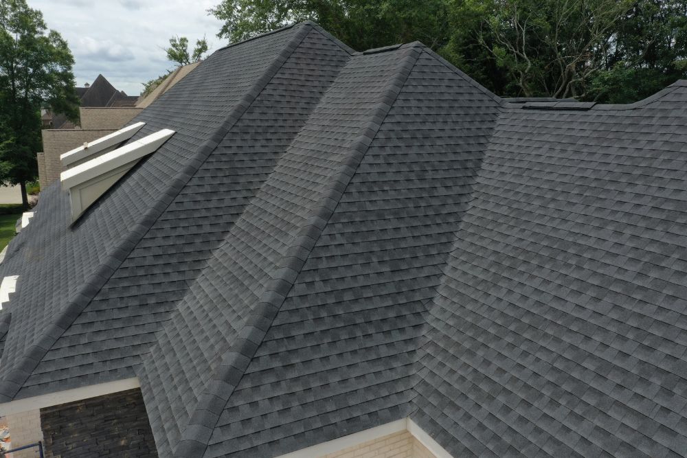 High-angle view of a completed Anoka MN roof replacement featuring dark charcoal architectural shingles on a multi-gabled home.