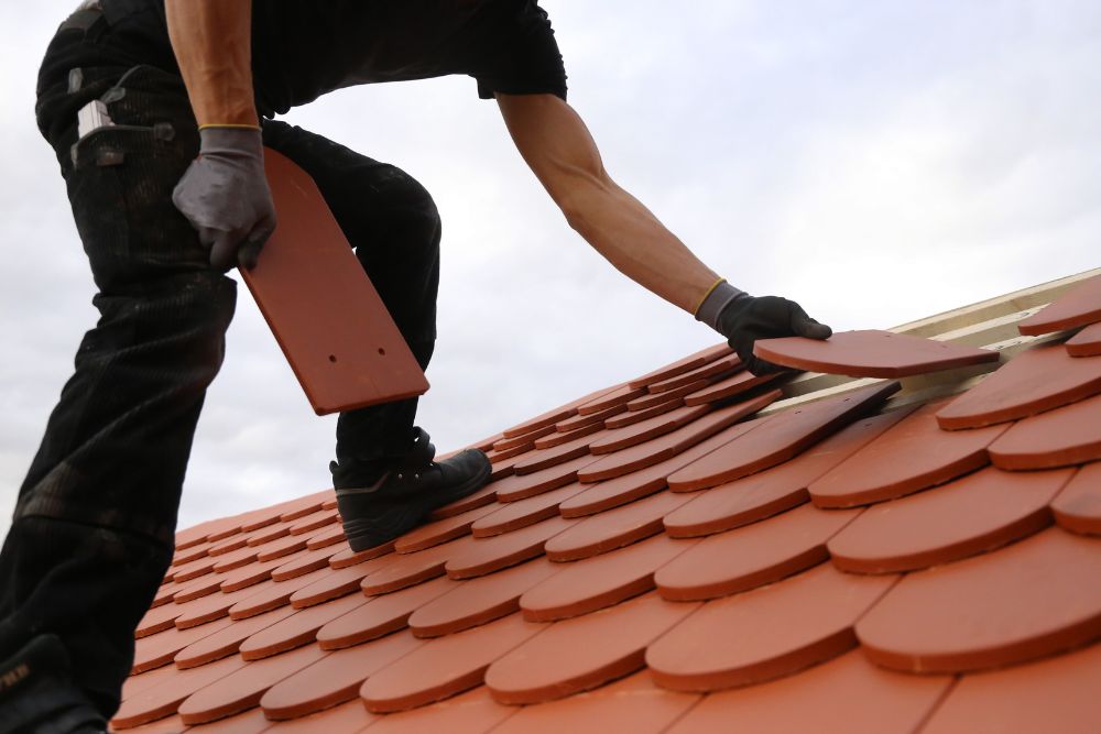 Professional roofing contractor installing terracotta-colored tiles during an Anoka MN roof replacement.