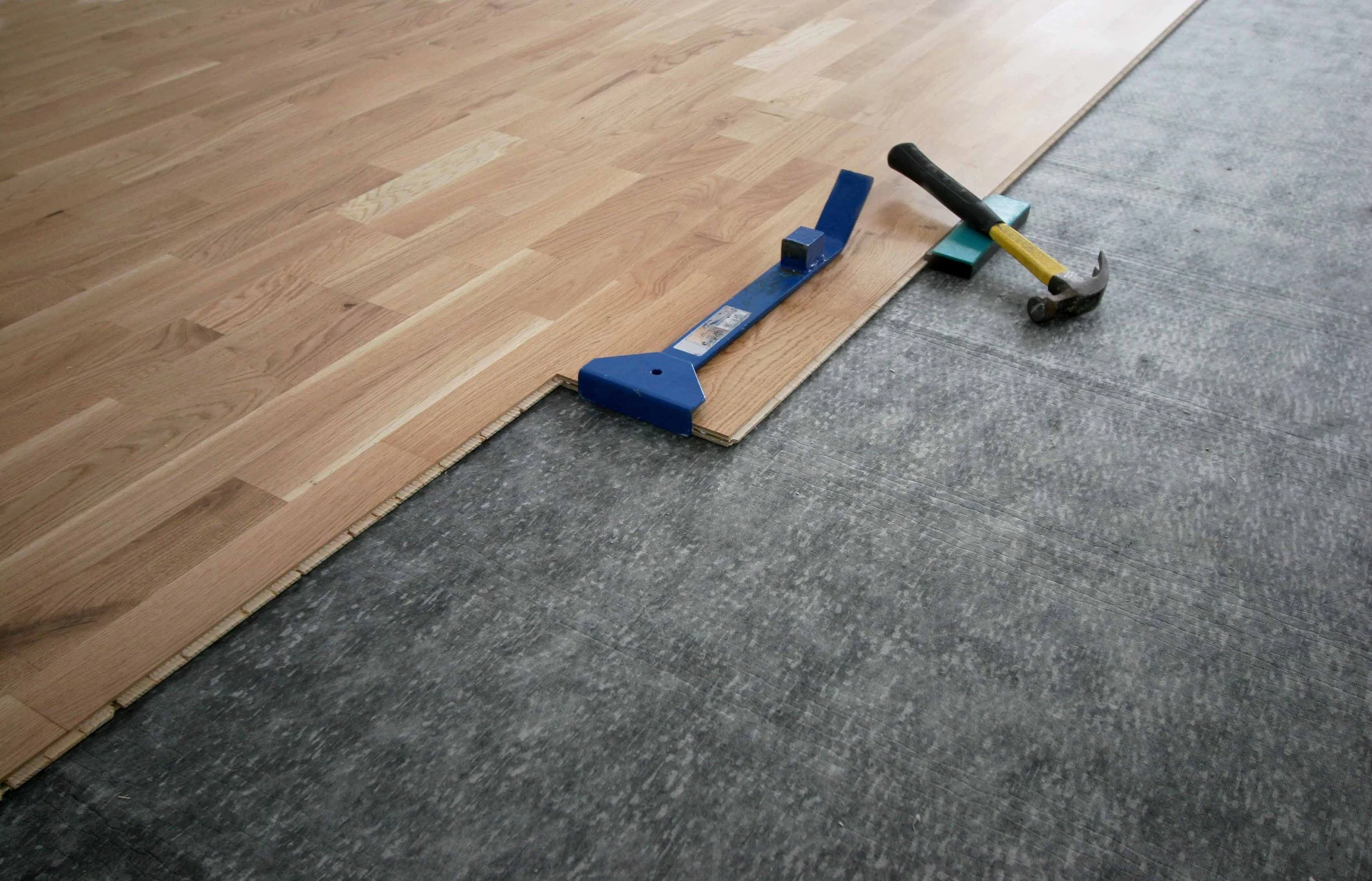 Commercial Flooring Installation Marietta GA by Peachy Flooring Solutions: Wood planks, installation tools, and underlayment.