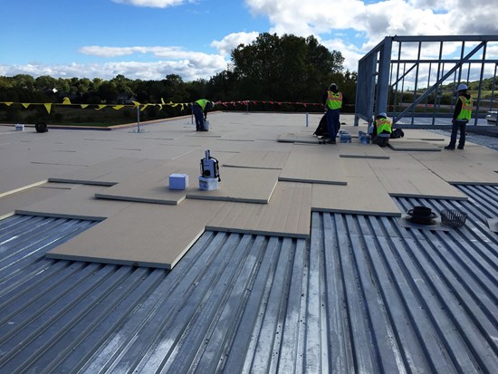 Commercial Roofing Services Franklin NC by Burish Builders Asheville: Crew installing insulation panels on a metal deck.