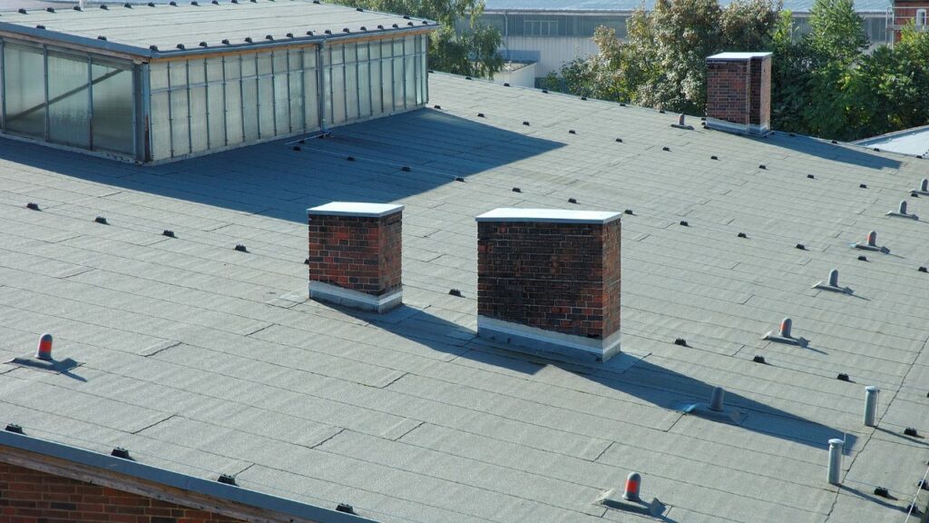 Commercial Roofing Services Franklin NC by Burish Builders Asheville: A grey flat roof with chimneys and skylight windows.