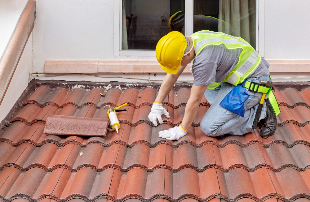 Expert Roof Maintenance Franklin NC by Burish Builders Asheville: technician repairing tile roofing with precision sealant.