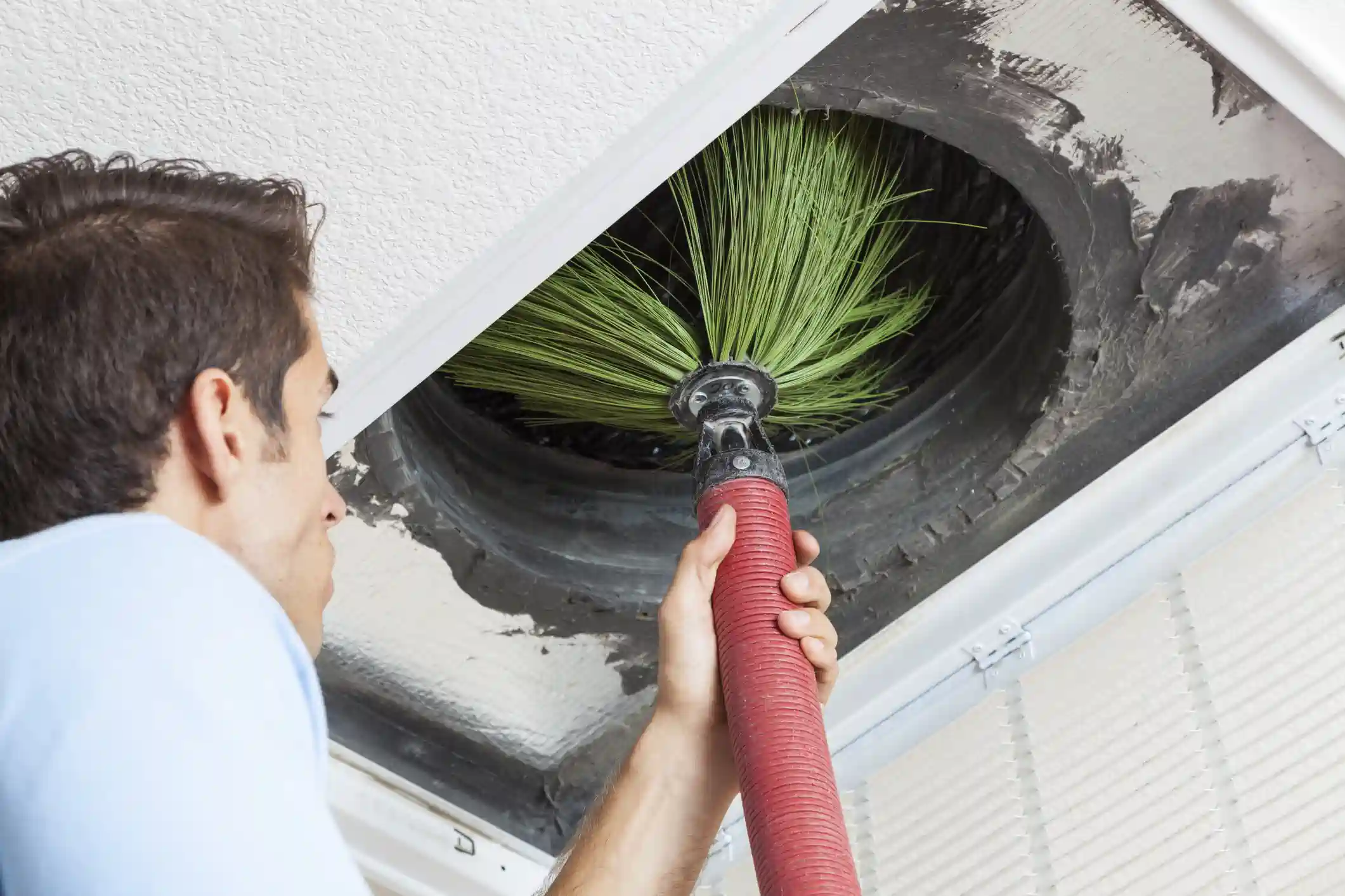 Commercial Airduct Cleaning Colorado Springs, CO by HP Duct Cleaning: Professional using a rotary brush to clear dust vents.