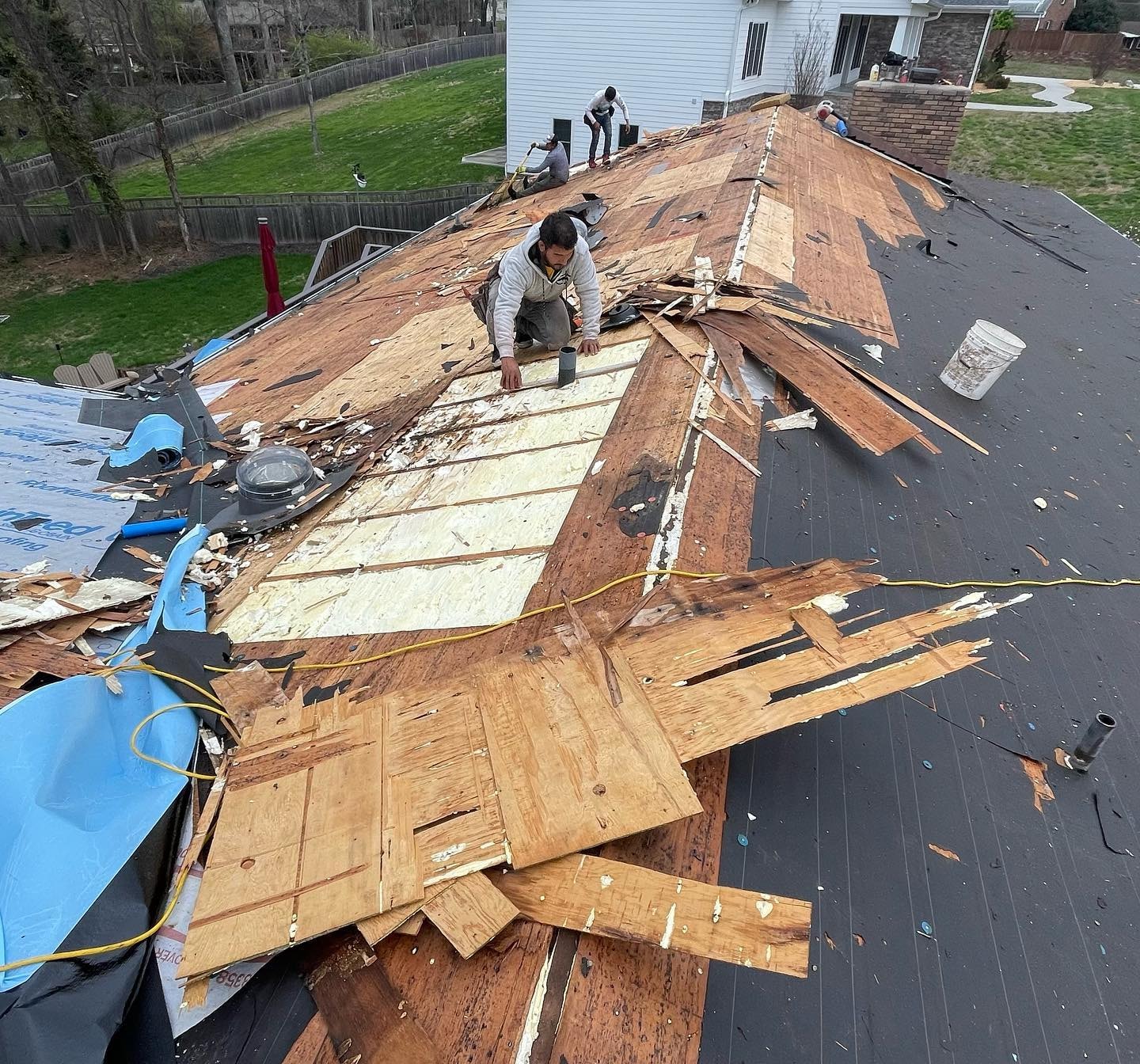 Roofers performing Edmond OK Storm Damage Roof Repair by Roof One, replacing plywood decking and underlayment on a home.