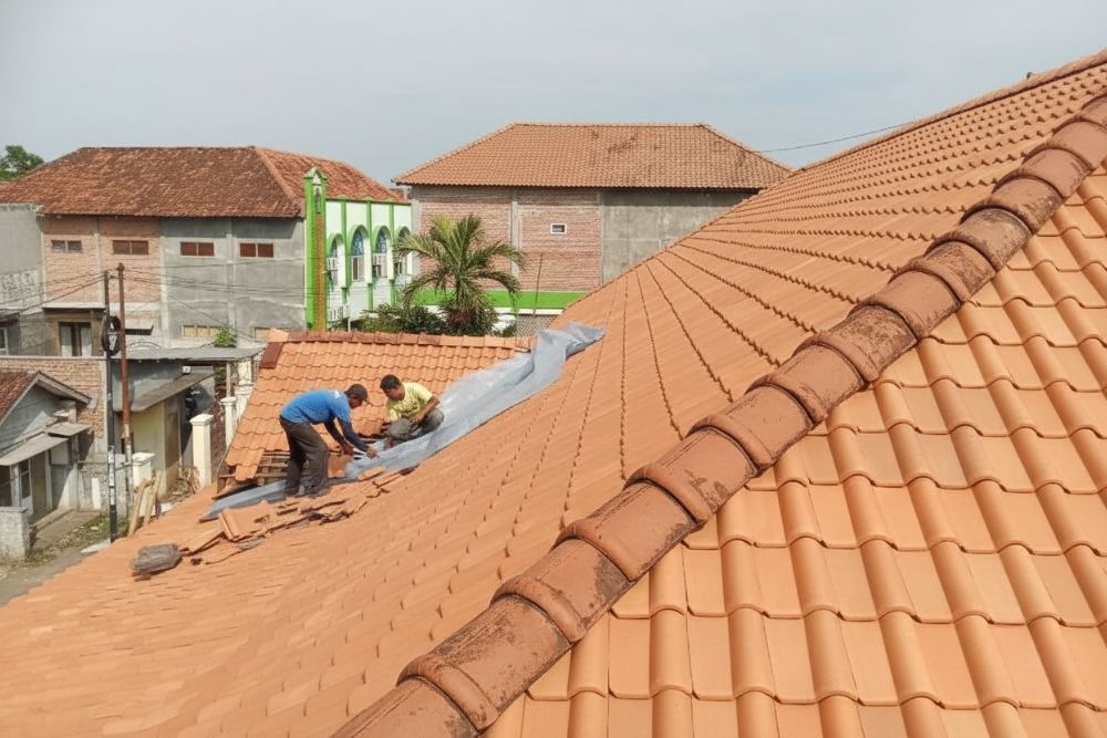Professional contractors performing a Florence Residential Roof Repair on a terracotta tile roof.