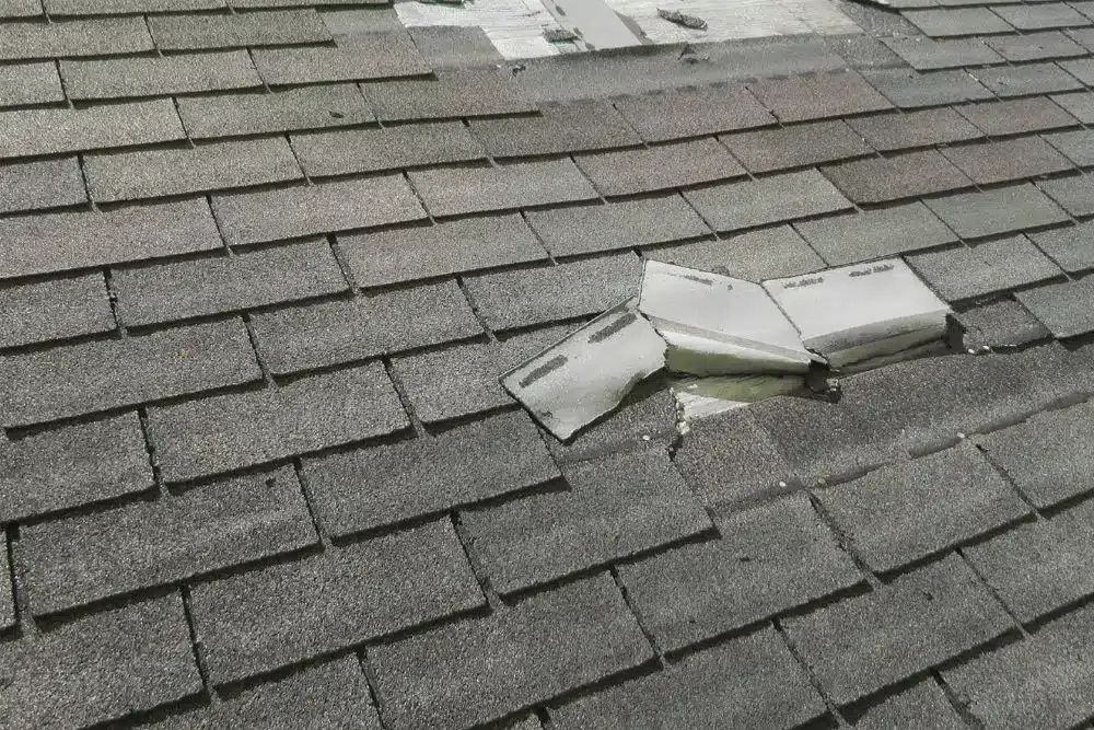 Close-up of punctured shingles and roof deck damage requiring Golden Valley MN commercial storm damage repair.