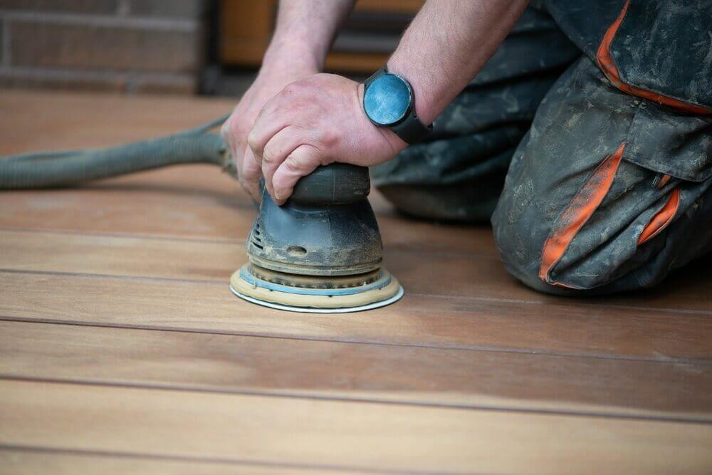 Hardwood Clean Buff Ballantyne NC by Good House Floor Care: A technician uses a handheld sander to prep wood floor planks.
