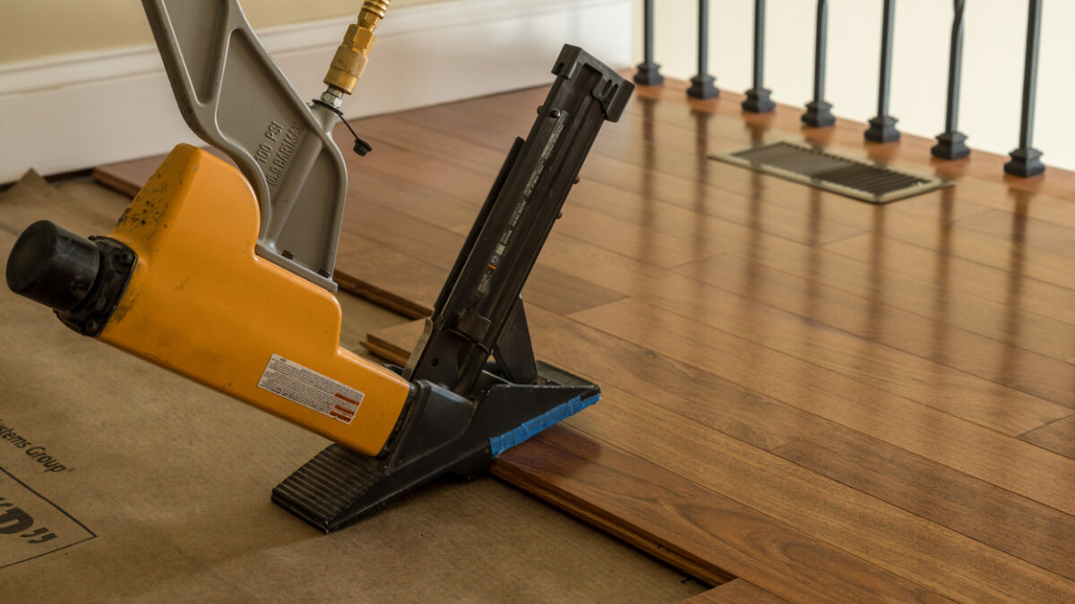 Professional Hardwood Floor Installation Ballantyne NC by Good House Floor Care using a pneumatic floor nailer on planks.