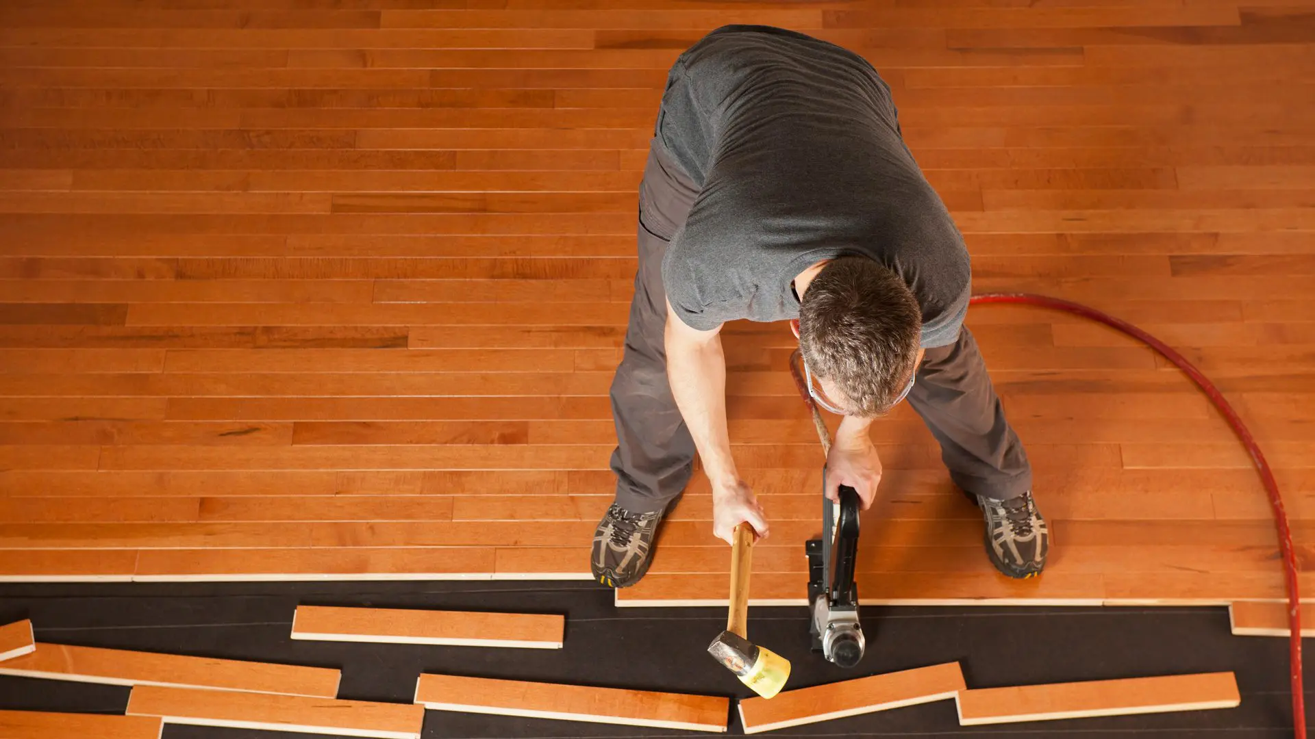 Expert hardwood floor installation Pineville NC with mallet and flooring jack by Good House Floor Care.