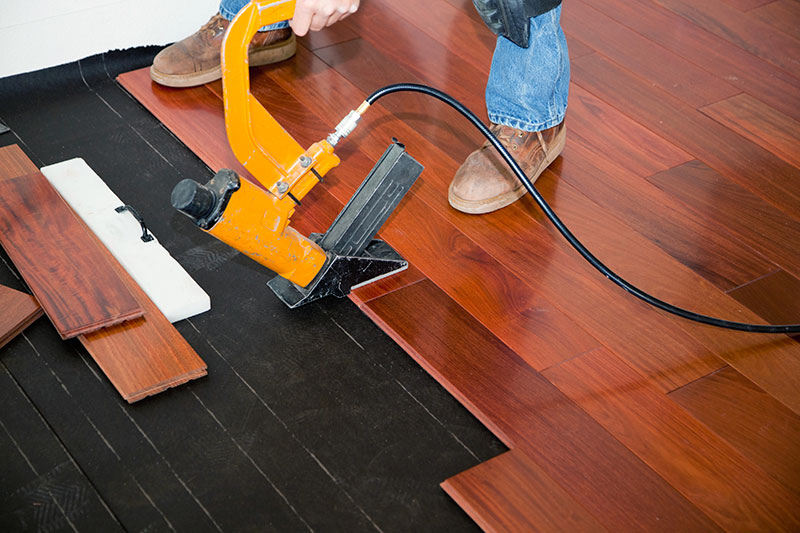 Professional hardwood floor installation Pineville NC using a pneumatic nailer by Good House Floor Care.