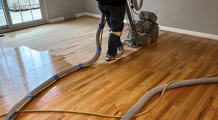 Professional Hardwood Floor Refinishing Ballantyne NC by Good House Floor Care featuring a drum sander removing old finish.