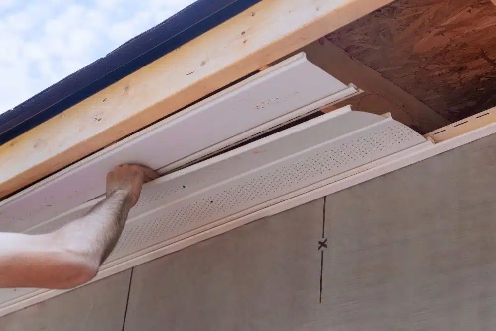 Close-up of Residential Siding Contractor Scott MN fitting vented soffit panels into a roof overhang.