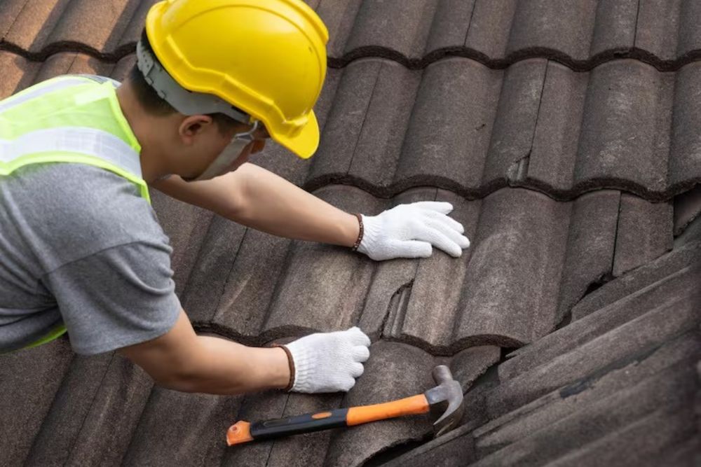 Close-up of a technician from Winston Residential Roof Repair inspecting damaged roof tiles for replacement.