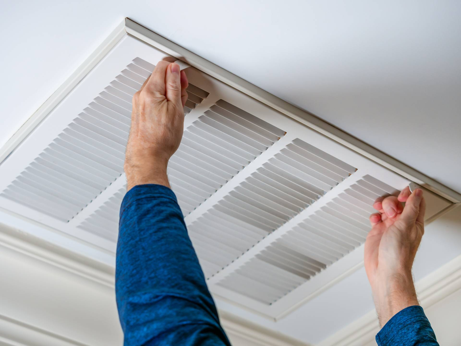 Air Duct Cleaning Colorado Springs CO by Premier Carpet Cleaning: Technician opening a ceiling intake vent for inspection.