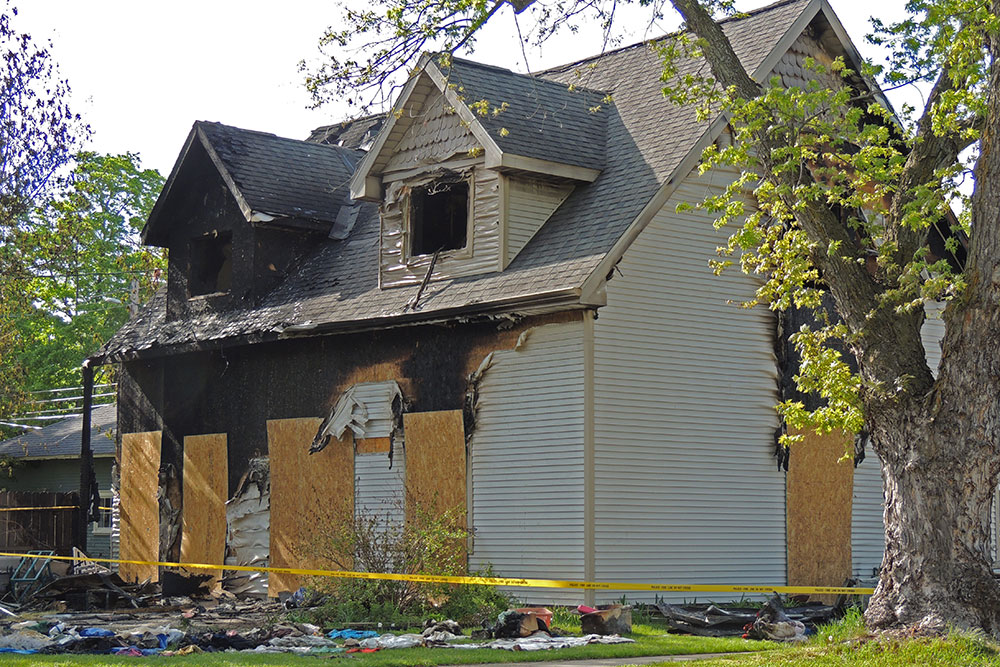 Fire Board Up Colorado Springs CO by Premier Carpet Cleaning: Plywood covers a house damaged by fire behind caution tape.