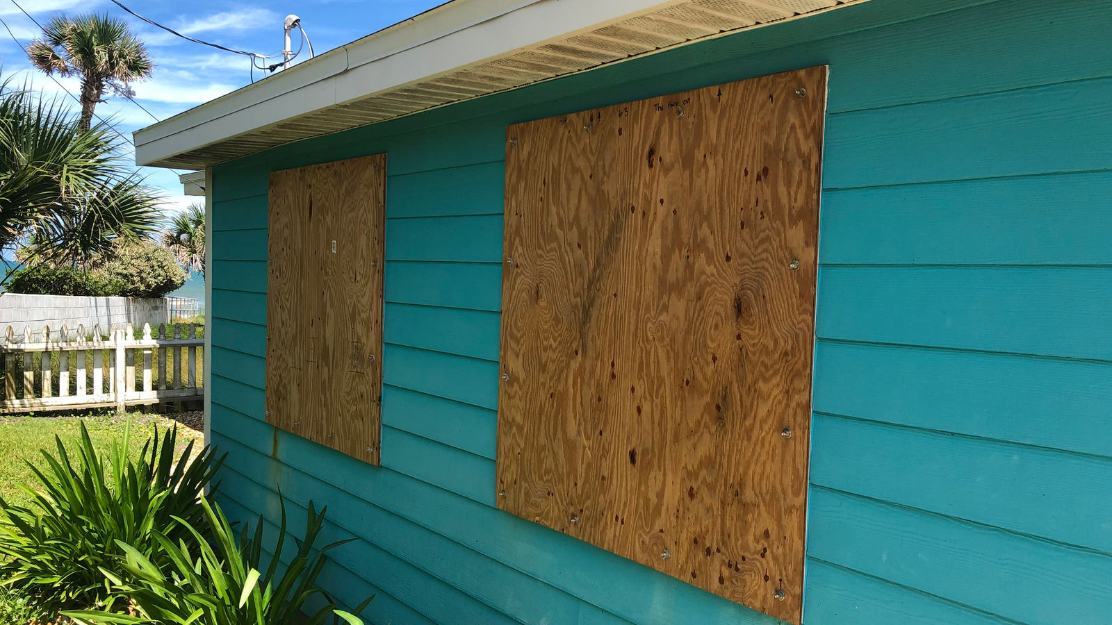 Fire Board Up Colorado Springs CO by Premier Carpet Cleaning: Secure plywood window covers installed on a blue home's exterior.