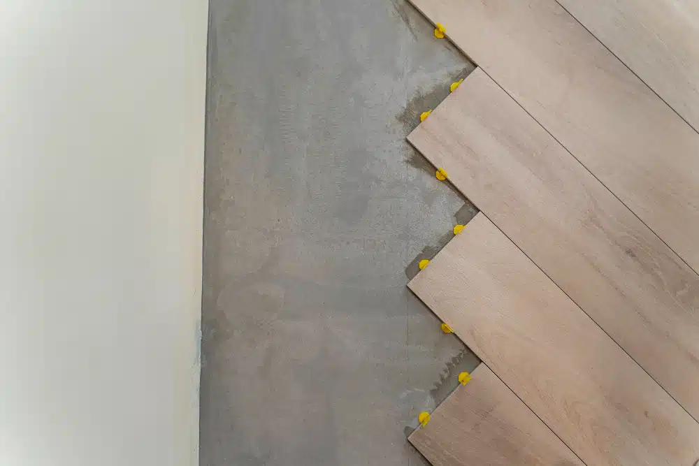 Professional Canton GA hardwood floor installation showcasing a diagonal plank layout with yellow leveling spacers on a grey subfloor.