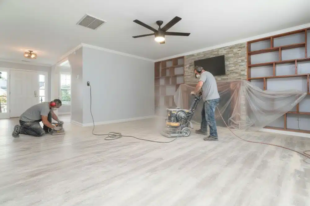 Professional team performing Decatur, GA hardwood floor refinishing using heavy-duty sanding equipment in a modern living room.
