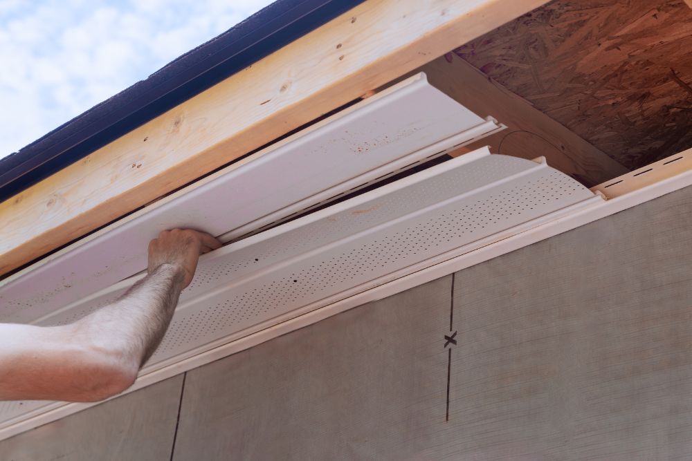 Eugene Residential Siding Repair: Contractor installing or repairing white perforated vinyl soffit/siding on a home's overhang.