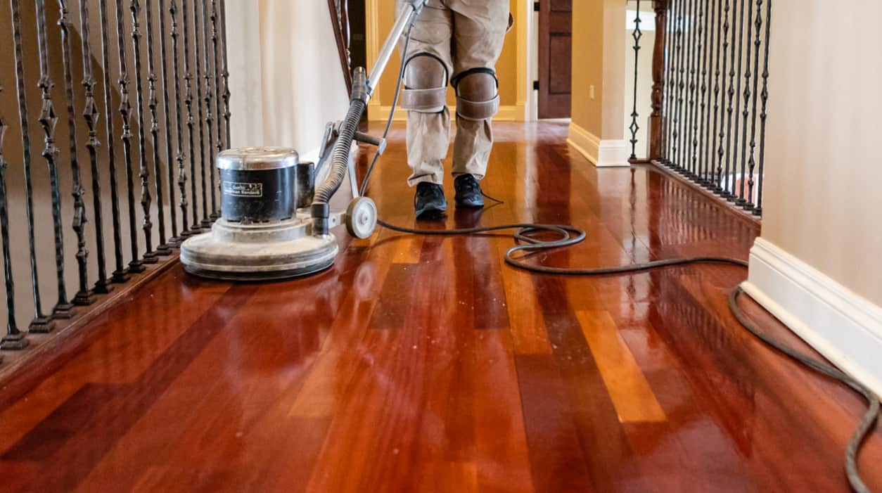 Hardwood Clean Buff Monroe NC by Good House Floor Care: Technician using a floor buffer to restore cherry wood hallway.