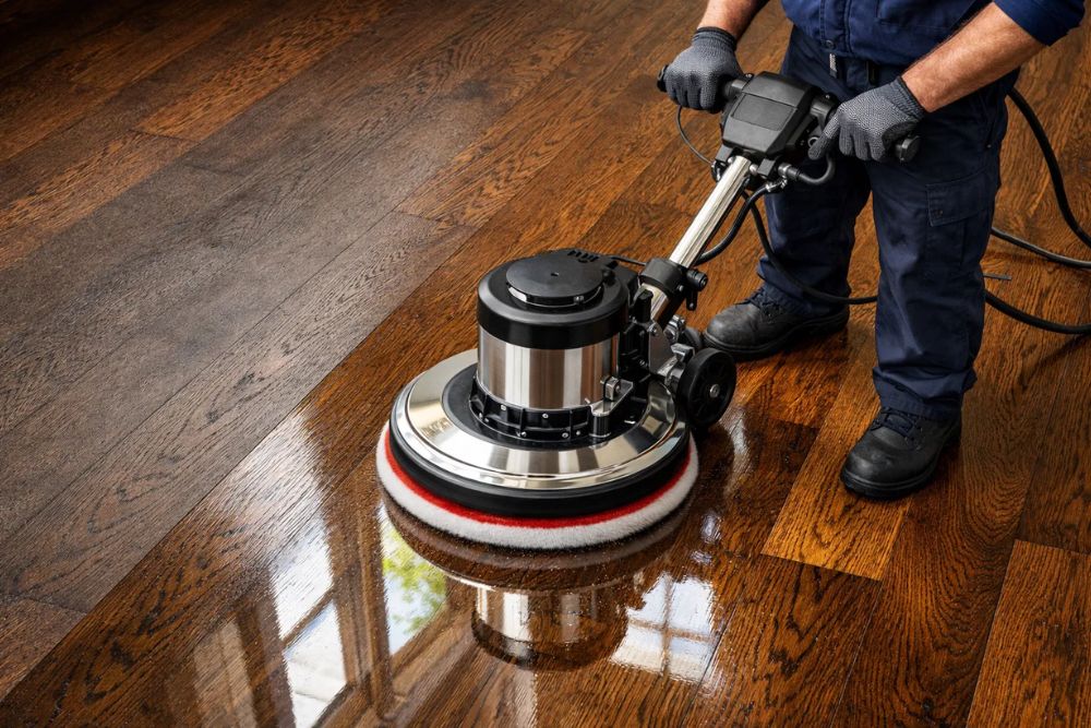 Professional hardwood floor polishing in Seattle WA, showing a technician using a buffer on a dark oak floor.