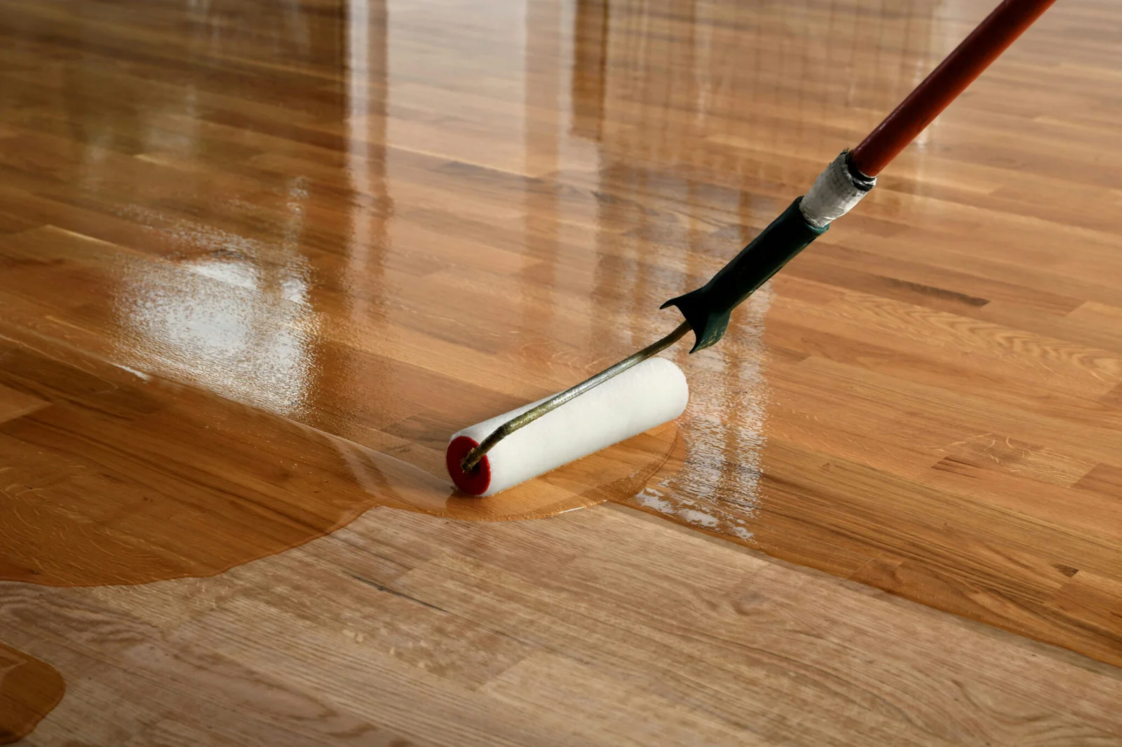 Hardwood Floor Screen and Recoat Monroe NC by Good House Floor Care: A professional applying a fresh finish with a roller.