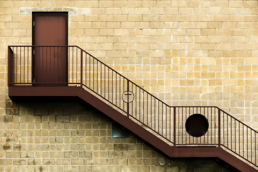 Johns Creek, GA staircase and handrail installation: exterior metal fire escape against brick wall.