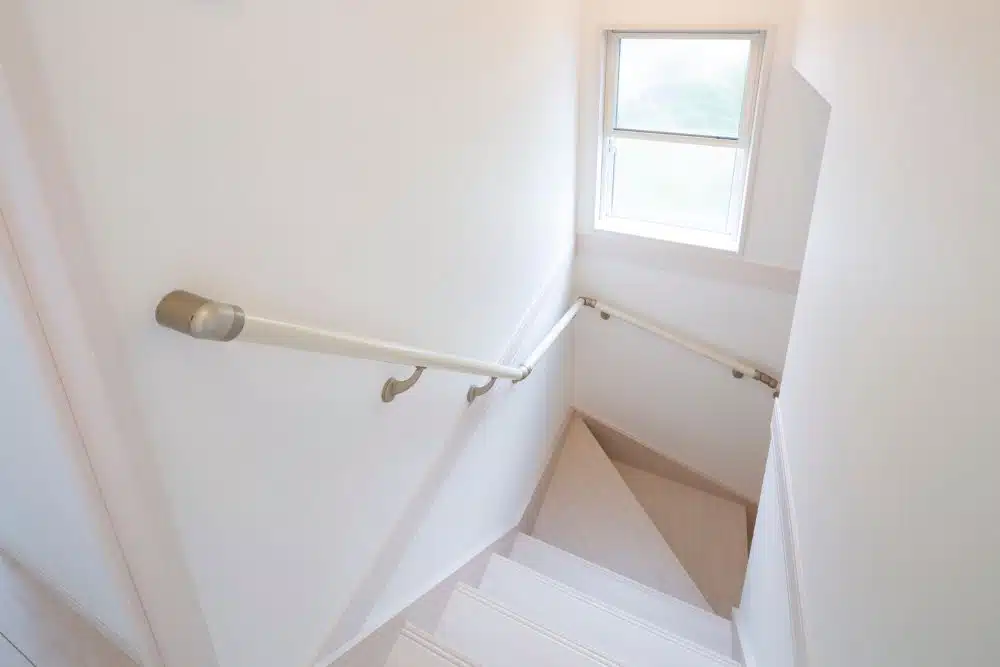 North Atlanta GA Staircase and Handrail Installation - Residential interior with a white-painted wooden staircase and supportive cream-colored ADA-compliant handrails.