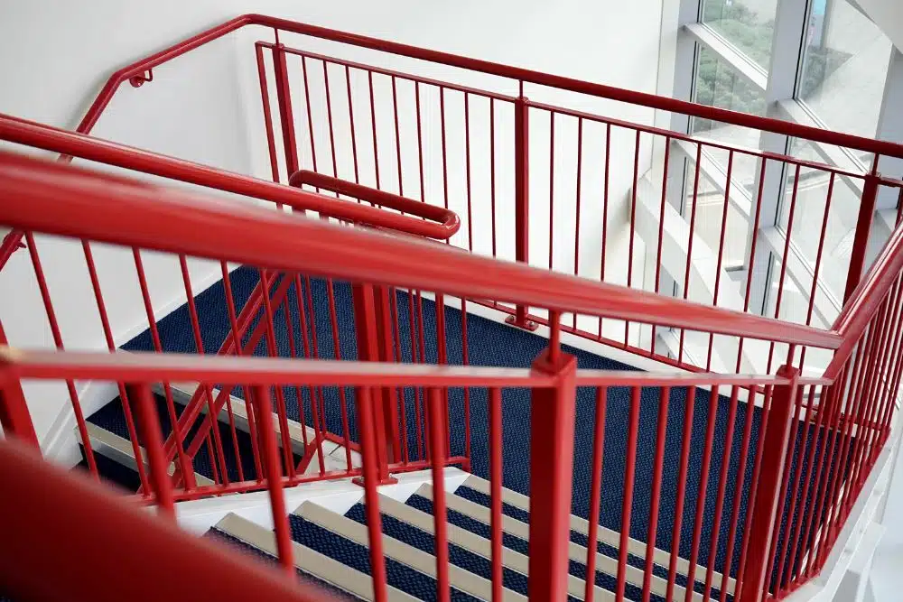 North Atlanta GA Staircase and Handrail Installation featuring a modern industrial design with bright red metal railings and blue carpeted stairs.