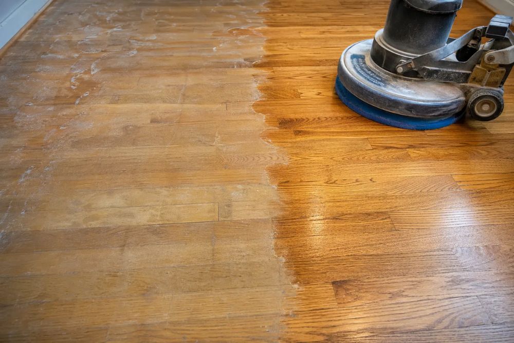 Professional hardwood floor wax removal in Lynnwood WA, showing a machine cleaning old wax to reveal natural wood.