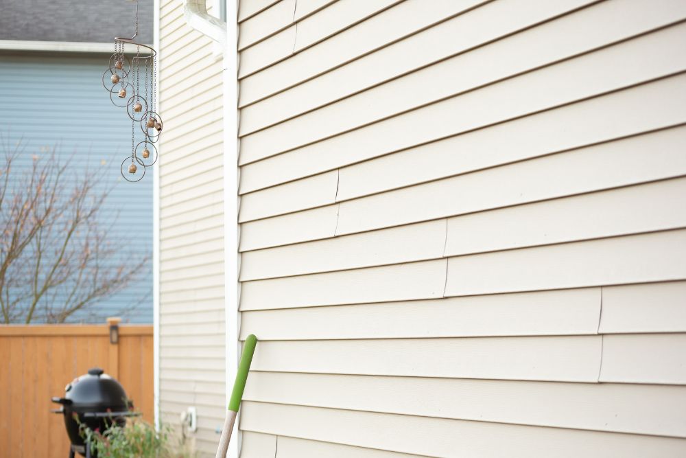 Close-up of beige horizontal vinyl siding on a residential home in Eugene, showing minor wear and corner trim, suggesting a need for Eugene Residential Siding Replacement.