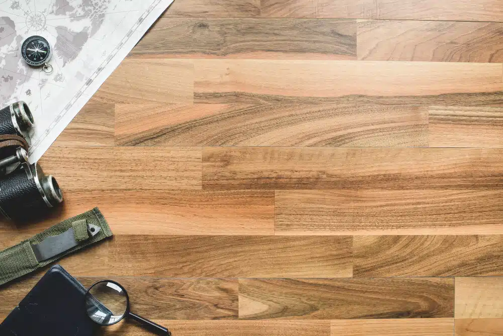 Wide view of multi-toned hardwood floor with map, binoculars, and magnifying glass, suggesting adventure. Johns Creek, GA Hardwood Floor Refinishing.